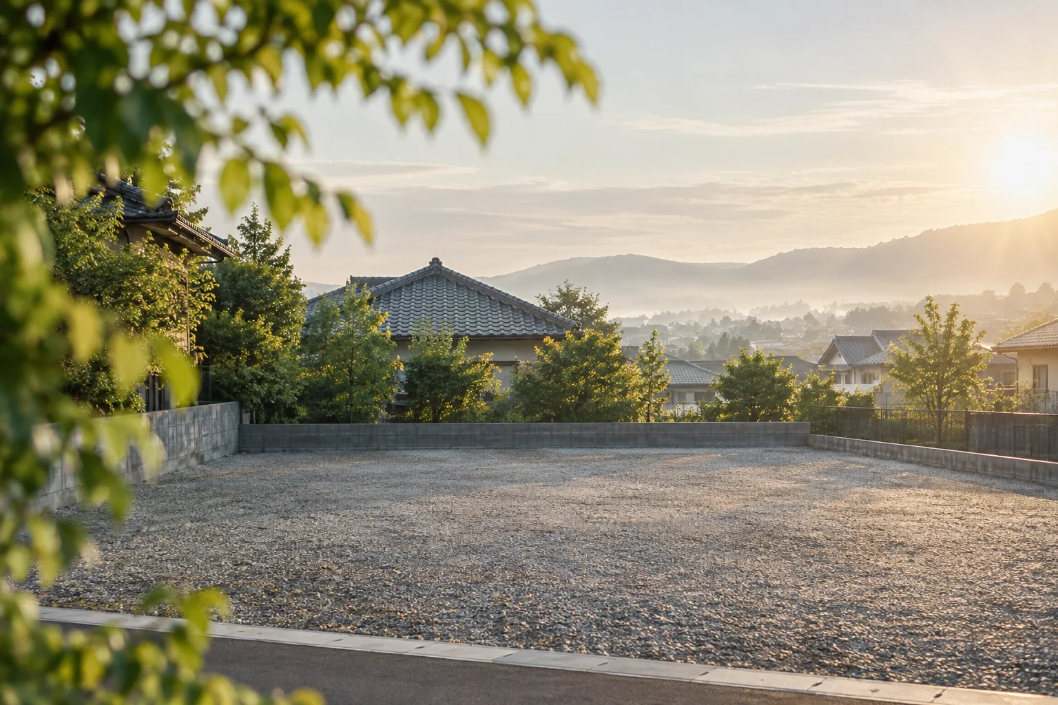 木々の向こうに住宅地と山並みが広がる更地のイメージ（AI生成）